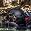 Person scuba diving in a natural water setting with trees in the background