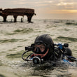 Person scuba diving in the ocean with a sunken structure in the background