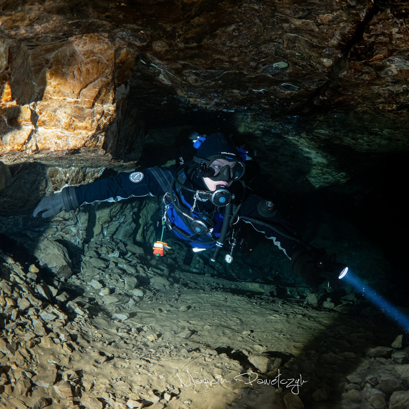 Scuba diver exploring a dark cave with a flashlight