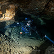 Scuba diver exploring a dark cave with a flashlight