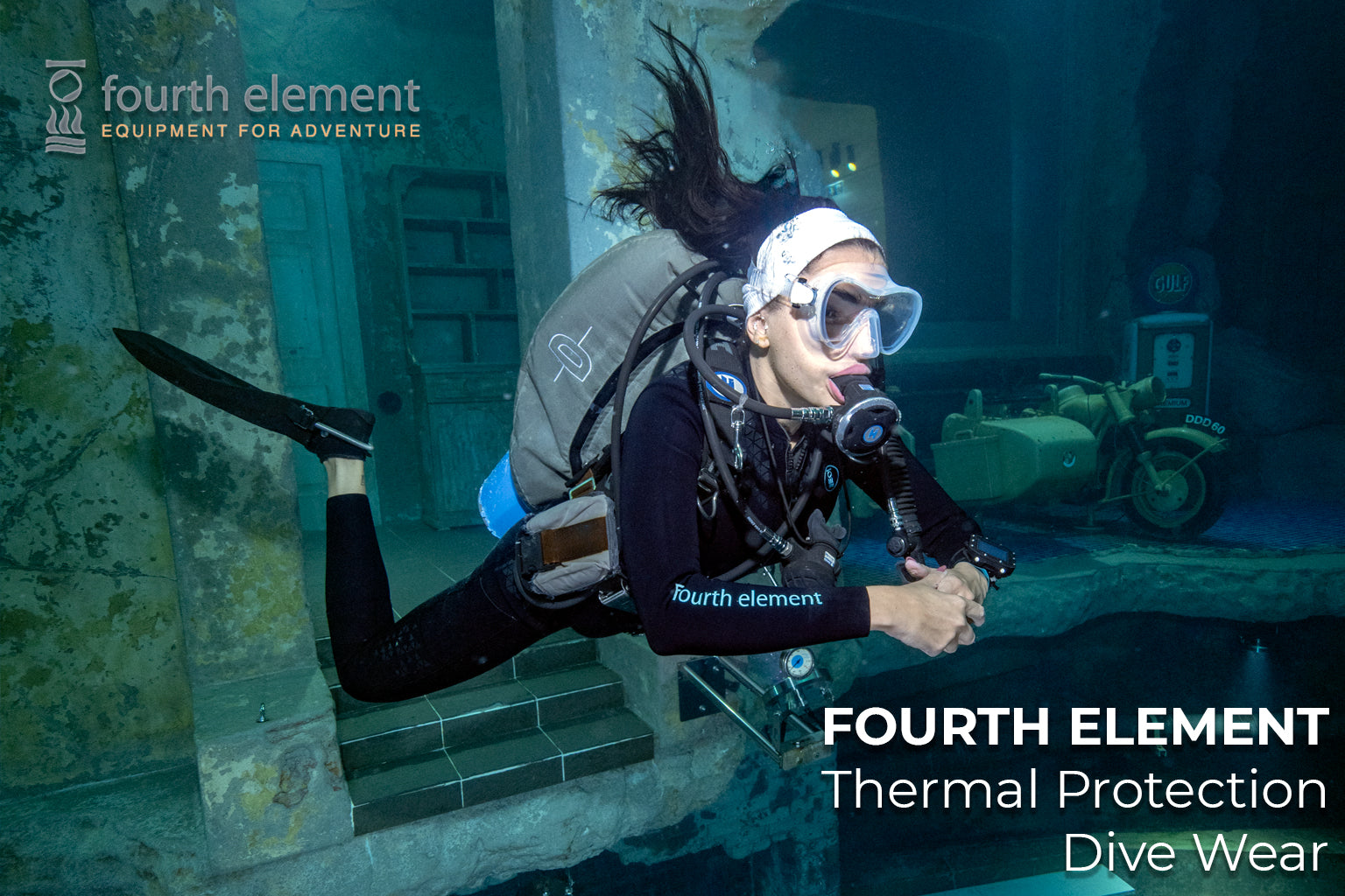 Person diving underwater with Fourth Element thermal protection dive wear branding.